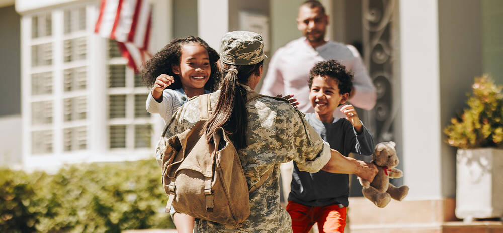 Children hugging a woman in military uniform.